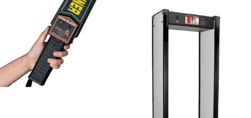 Security personnel using a walk-through metal detector at a public building entrance to prevent theft and violence in a crowded space.